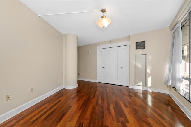 unfurnished bedroom with a closet, baseboards, visible vents, and wood finished floors