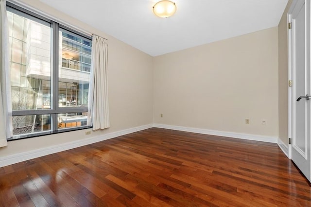 unfurnished room with baseboards and hardwood / wood-style floors