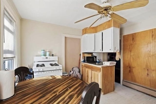 kitchen featuring ceiling fan, sink, a baseboard radiator, white cabinets, and white gas range oven