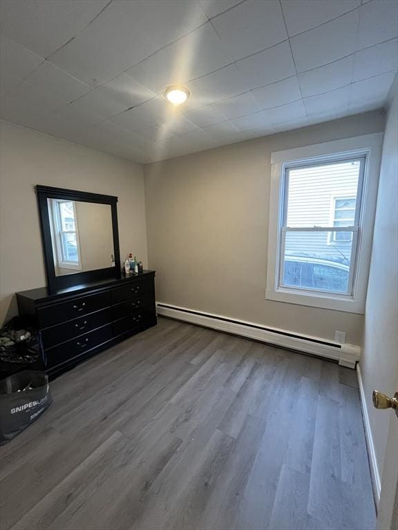 unfurnished bedroom featuring hardwood / wood-style floors and a baseboard radiator