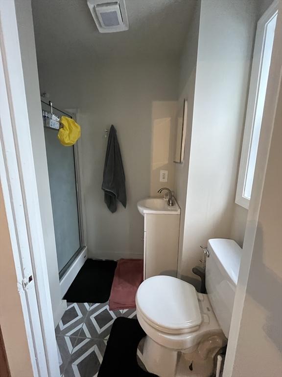 bathroom with vanity, toilet, and a shower with door