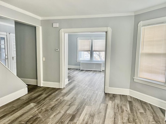 unfurnished room with ornamental molding, baseboards, radiator heating unit, and wood finished floors