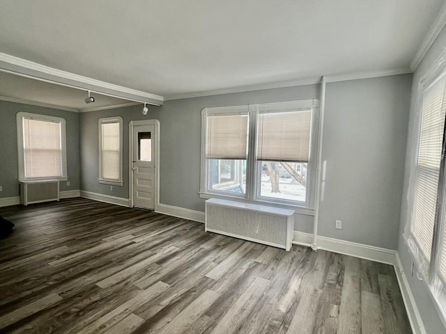 spare room featuring dark wood-style floors, baseboards, ornamental molding, and radiator heating unit