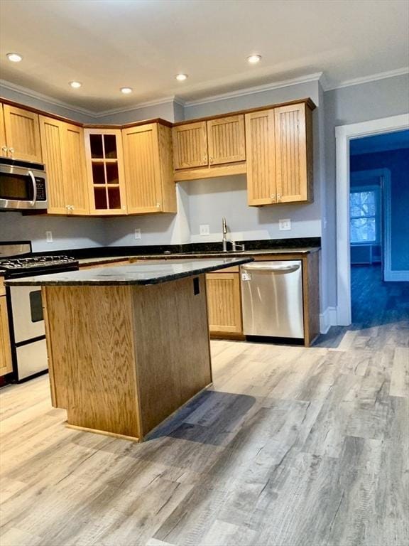 kitchen featuring stainless steel appliances, dark countertops, a center island, and light wood-style floors