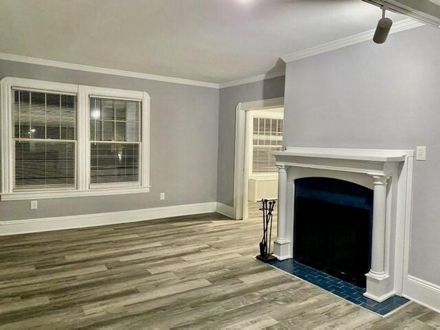 unfurnished living room featuring ornamental molding, wood finished floors, and baseboards