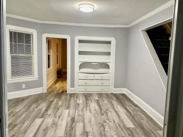 interior space with crown molding, baseboards, and wood finished floors