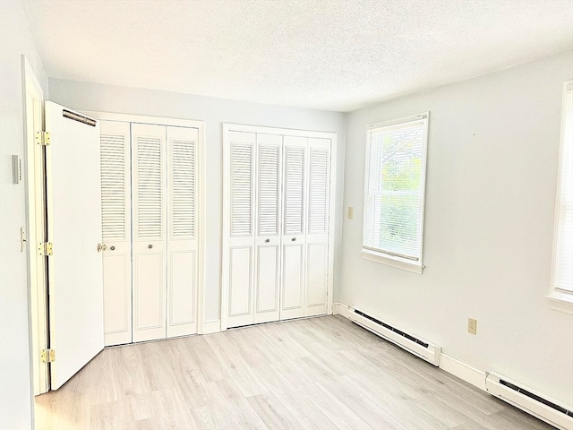 unfurnished bedroom with light wood-type flooring, a textured ceiling, and baseboard heating