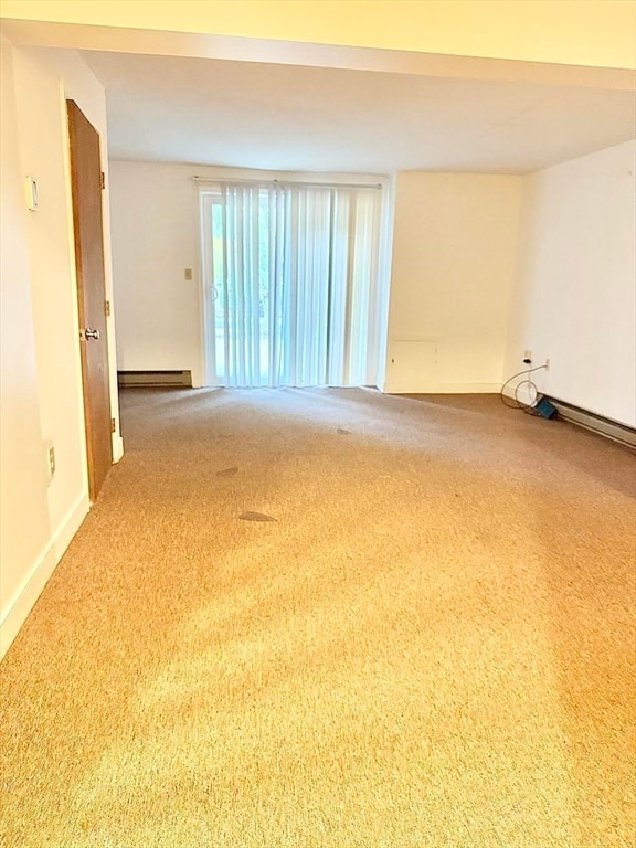 unfurnished room featuring carpet flooring and a baseboard heating unit