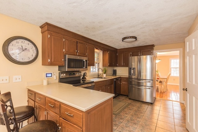 kitchen with stainless steel appliances, a textured ceiling, and sink