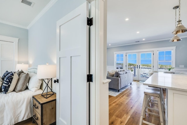 bedroom featuring french doors, ornamental molding, light wood-type flooring, and access to exterior