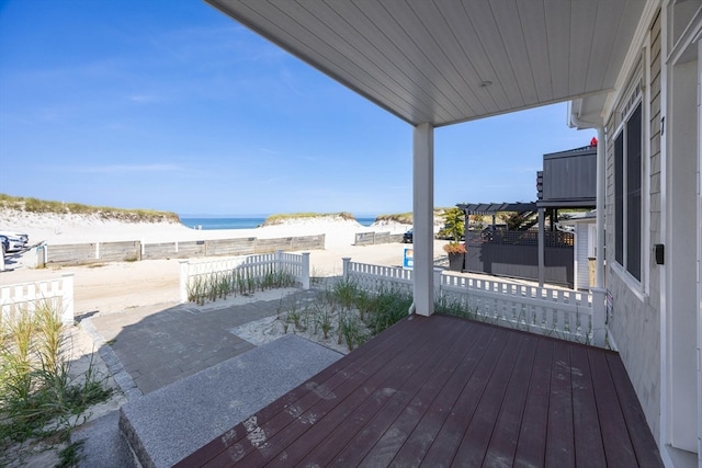 wooden terrace featuring a beach view and a water view