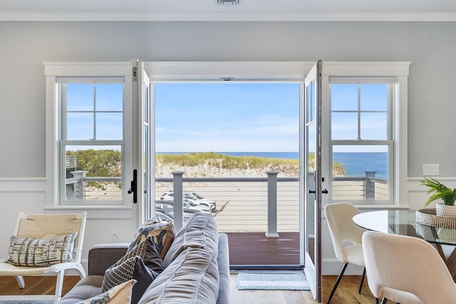 doorway featuring light wood-type flooring, a water view, and crown molding