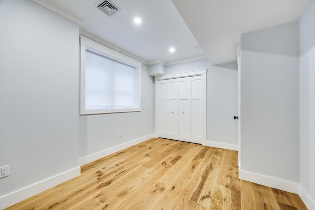 unfurnished bedroom with light wood-type flooring, crown molding, and a closet