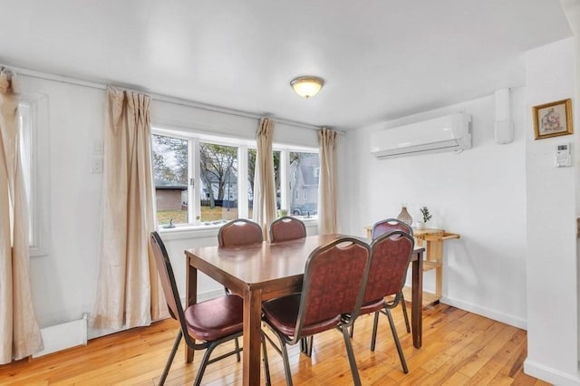 dining area with a wall mounted air conditioner and light hardwood / wood-style flooring