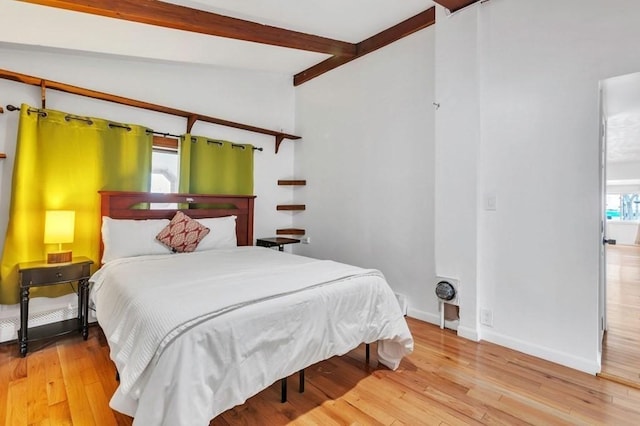 bedroom featuring vaulted ceiling with beams and hardwood / wood-style floors