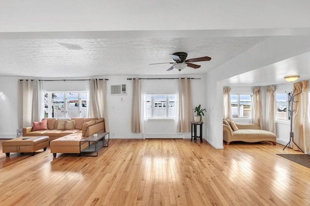 living room featuring light hardwood / wood-style flooring, an AC wall unit, a textured ceiling, and a baseboard heating unit