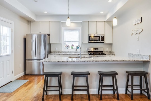 637 Gifford St Unit 4A, Falmouth, MA 02540 - kitchen featuring stainless steel appliances, light stone counters, a kitchen bar, decorative light fixtures, and recessed lighting