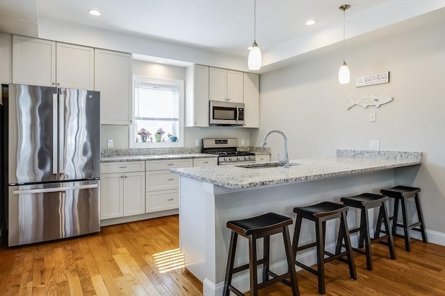 637 Gifford St Unit 4A, Falmouth, MA 02540 - kitchen with stainless steel appliances, a peninsula, a kitchen bar, light wood-style floors, and hanging light fixtures