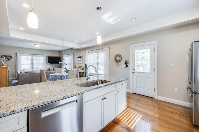 637 Gifford St Unit 4A, Falmouth, MA 02540 - kitchen featuring appliances with stainless steel finishes, white cabinetry, a tray ceiling, light wood-style floors, and light stone counters
