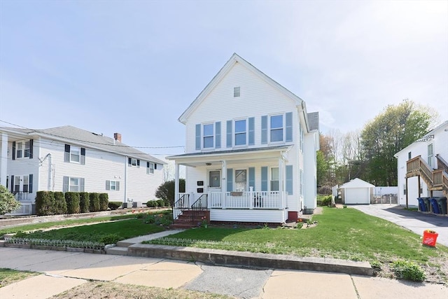 view of front of property with covered porch, an outbuilding, a front lawn, and a detached garage