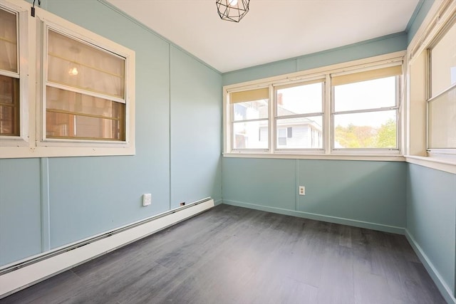 empty room featuring baseboards, a baseboard radiator, and wood finished floors