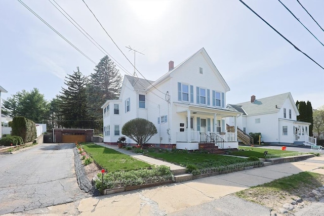 view of front of property with a detached garage, covered porch, a chimney, and a front yard