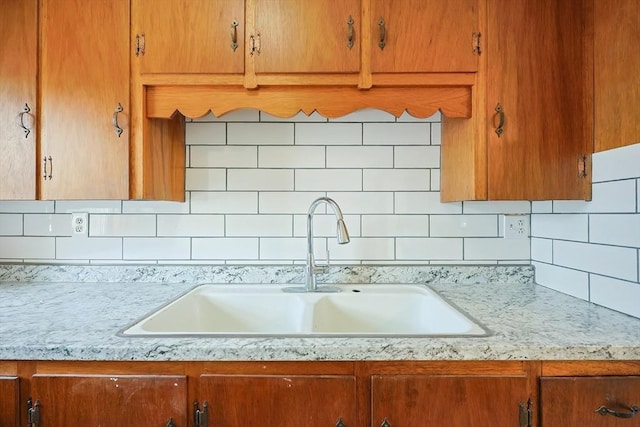 kitchen with a sink, decorative backsplash, and brown cabinets