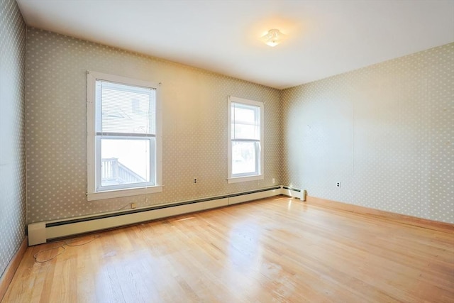 unfurnished room featuring baseboards, baseboard heating, wallpapered walls, and wood finished floors