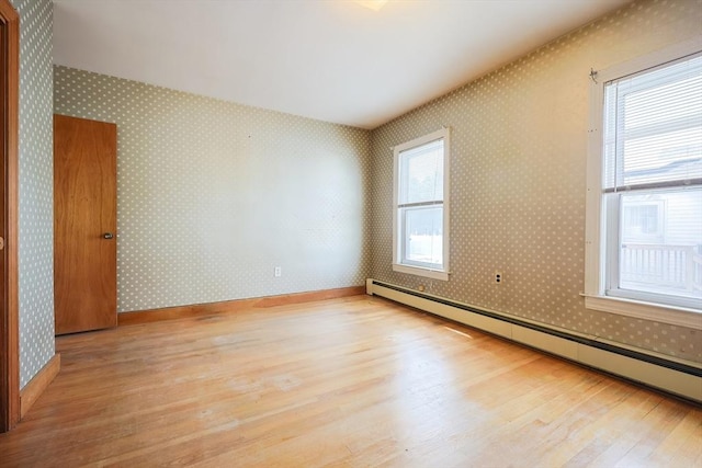 spare room featuring a baseboard radiator, wood finished floors, and wallpapered walls