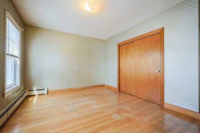 unfurnished bedroom with wallpapered walls, light wood-style flooring, and a closet
