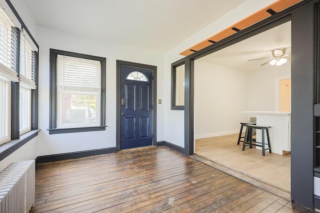 foyer entrance with baseboards, a ceiling fan, radiator, and hardwood / wood-style flooring