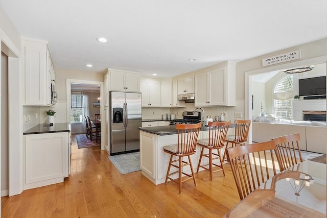 kitchen with under cabinet range hood, a healthy amount of sunlight, dark countertops, and stainless steel appliances