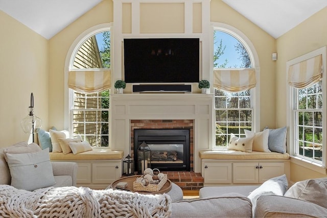 living area with a brick fireplace and lofted ceiling