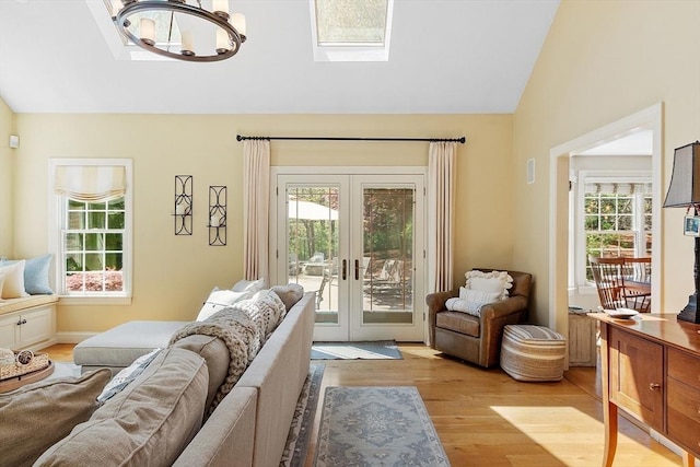 living area with a wealth of natural light, french doors, vaulted ceiling with skylight, and light wood-type flooring