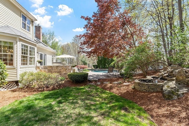 view of yard with an outdoor pool and an outdoor fire pit