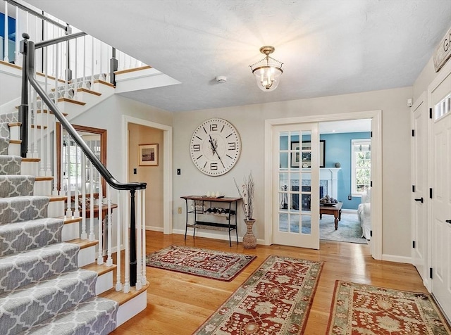 entrance foyer with baseboards, stairs, wood finished floors, and an inviting chandelier
