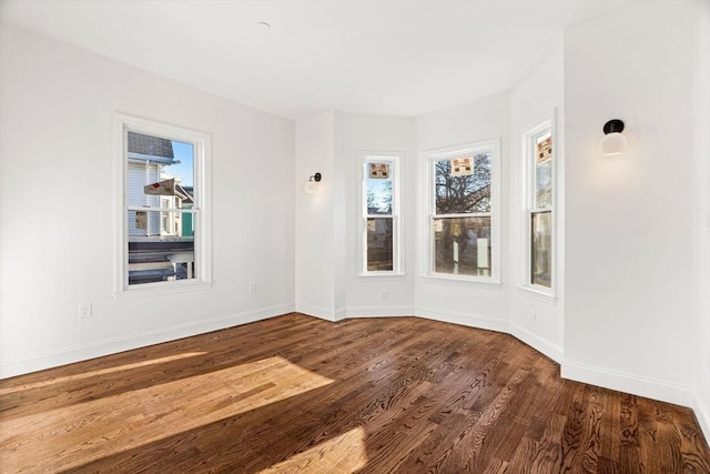 unfurnished room featuring a healthy amount of sunlight and dark hardwood / wood-style floors