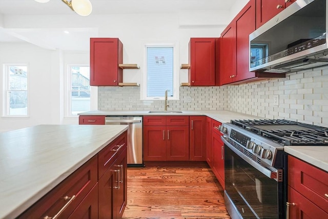 kitchen with tasteful backsplash, sink, stainless steel appliances, and light hardwood / wood-style floors