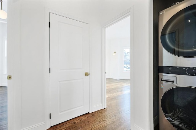 washroom featuring hardwood / wood-style flooring and stacked washing maching and dryer