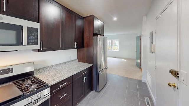 kitchen with stainless steel appliances, light carpet, dark brown cabinetry, and light countertops