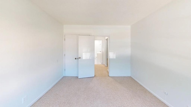 empty room with baseboards and light colored carpet