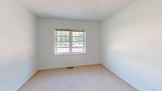 carpeted empty room with visible vents, a textured ceiling, and baseboards