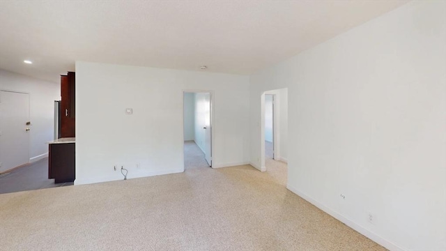 unfurnished room with baseboards and light colored carpet