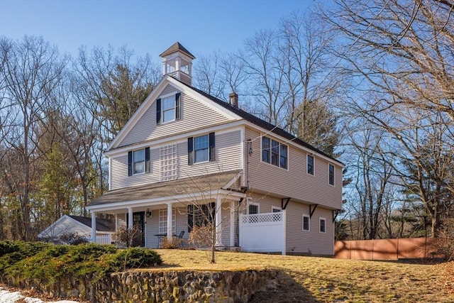 view of front facade with fence, covered porch, and a chimney