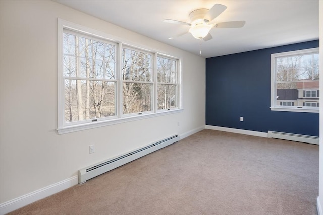 carpeted spare room with a baseboard radiator, baseboards, and ceiling fan