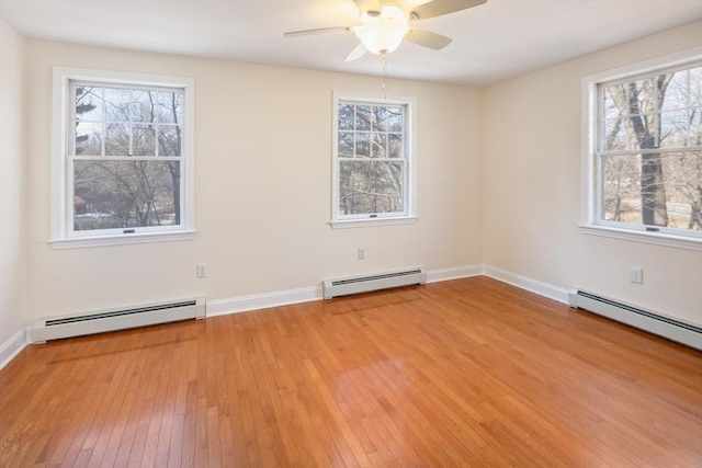 spare room featuring light wood-type flooring, a baseboard heating unit, and a wealth of natural light