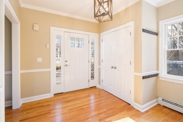 foyer entrance with crown molding, baseboards, baseboard heating, an inviting chandelier, and wood finished floors