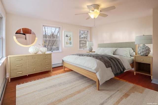 bedroom featuring a baseboard heating unit, wood finished floors, baseboard heating, and ceiling fan