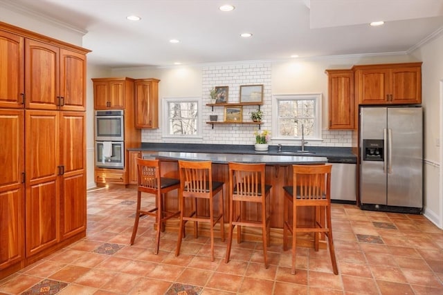 kitchen featuring a sink, brown cabinets, a wealth of natural light, and stainless steel appliances