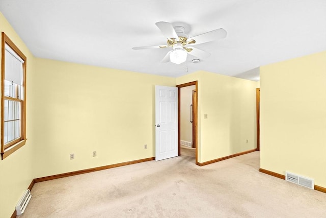 empty room featuring a baseboard radiator, light colored carpet, and ceiling fan